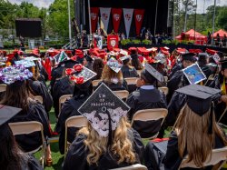 photo is taken looking towards the stage. student's graduation caps fill the image, some are decorated