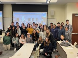 a group of students stand together in a classroom for a large group photo