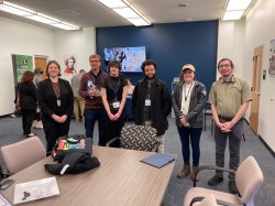 a group of students stand and pose for photo in a classroom