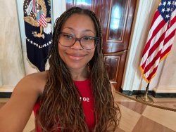 Photo of student Amiya Strother smiling with American Flags behind her