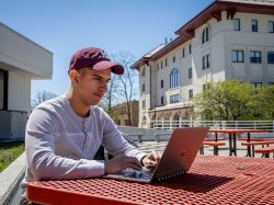 student with laptop sitting outside
