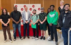 A group of students and an executive from WNBC in front of a branded backdrop/