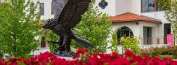 Photo of Bronze Red Hawk Statue with red azaleas