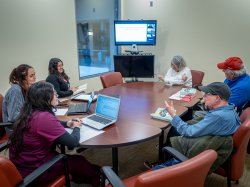 colleagues around a table, speaking to one another