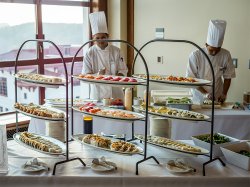 A variety of sushi options with some chefs preparing sushi in the background.