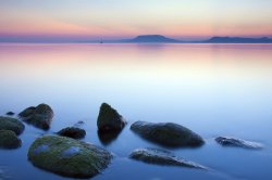 view of a lake at sunset with some rocks