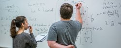 students writing mathematical equations on whiteboard