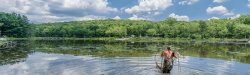 Student with a dragnet walking in lake.
