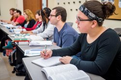 Student taking notes in class and following the lecture.