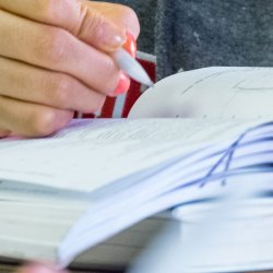 Close up of a book and a student writing.
