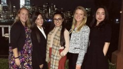 Students standing in front of NYC skyline at night