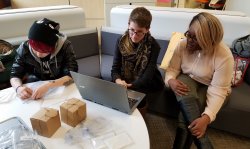 Three female students sit at laptop, working on group project, in the Feliciano Center office