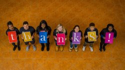 Students holding signs spelling the word Thanks.