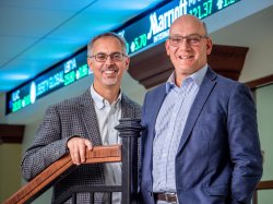 Merli and Radin in front of stock ticker