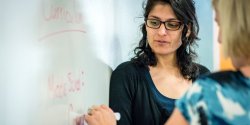 PhD student and professor work out a problem on a whiteboard
