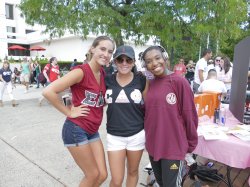Three students posing for a picture in their Greek gear in the quad.