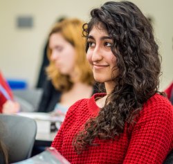 Photo of a smiling student sitting in a class.