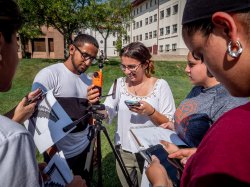Group of students conducting a science experiment about physics outside, while huddled in a group.