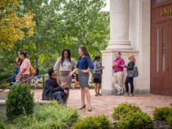 Students in professional dress smiling outside on campus