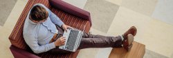 Top view of a student sitting with feet on a table working on a laptop
