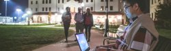 Student using a laptop while siting outside