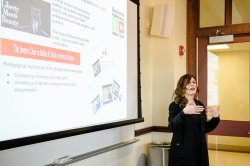 Photo of a speaker presenting in front of a screen.