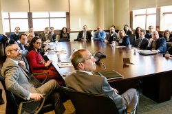 Photo of a group of individuals in a board room watching a presentation.