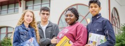 Image of four students standing outside of Schmitt Hall, posing for the camera.