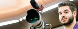 Image of a student with a video camera and mic filming an event.