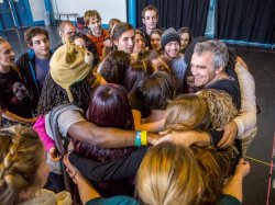 Image of a crowd smiling and holding hands in a group activity.