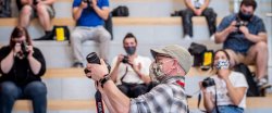 Male faculty in hat wearing facemask teaching class about cameras