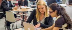 Two female students discussing and looking at a laptop screen