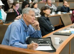 Audience paying attention to a lecture with older white male in foreground