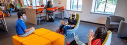 3 masked students in lounge setting discussing lesson