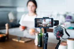 female in front of phone camera on tripod about to record video