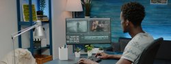 african american male videographer with headphones editing on desktop computer