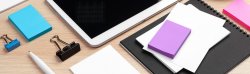Digital tablet with notepad, supplies on desk and coffee cup on desktop.