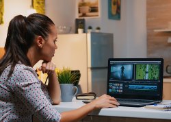 female videographer editing from home on professional laptop