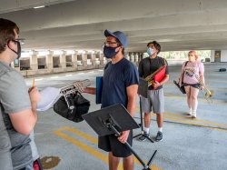 students holding stands and instruments speaking with each other