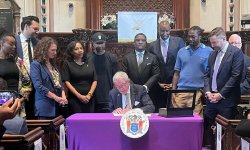 a group stands and looks on as NJ Governor Phil Murphy signs law