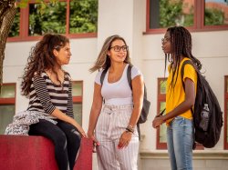 Three students on quad in front of school of nursing