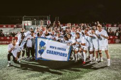 Men's soccer team posing behind banner