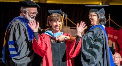 Dr. Peggy Flood being hooded by CSAM Dean Robert Prezant and Program Director Mika Munakata