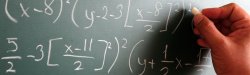 Hand writing mathematical formulas on a blackboard.