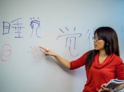 Professor Wing Shan Ho in front of white board with Chinese characters written on board