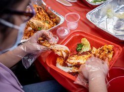 close view of student wearing gloves, rubbing spice on cabbage leaves