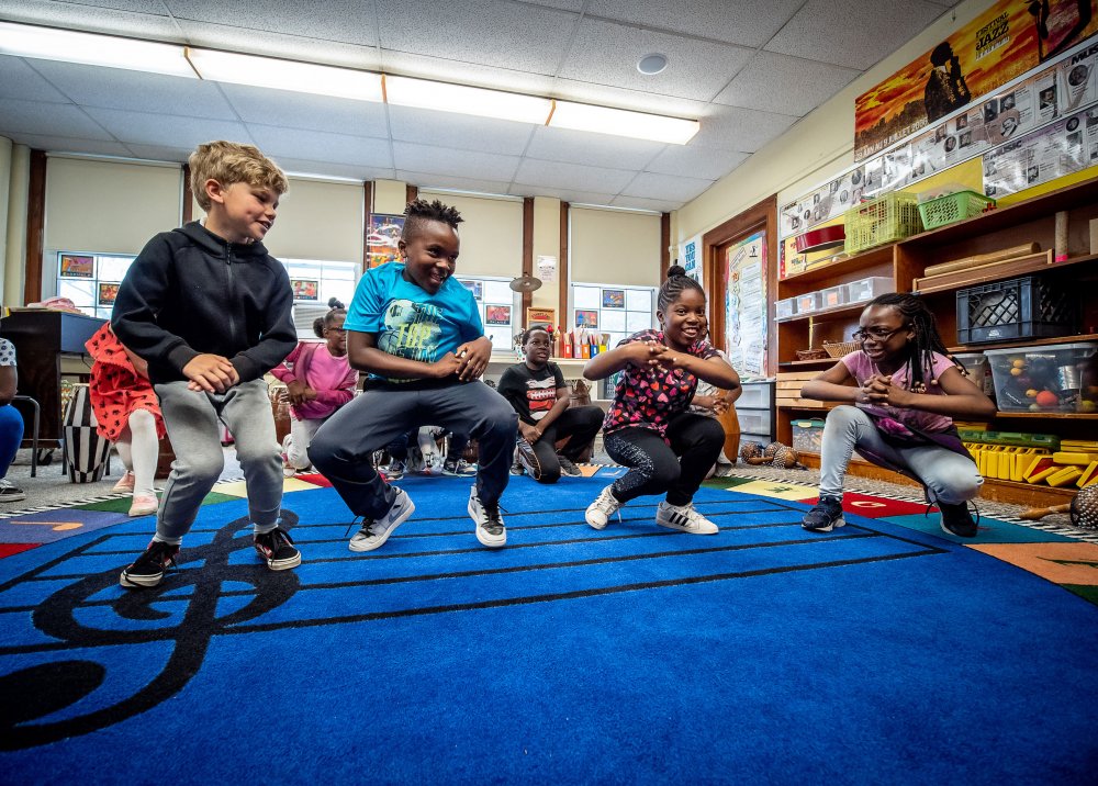 Four third grade students smiling and dancing to West African music