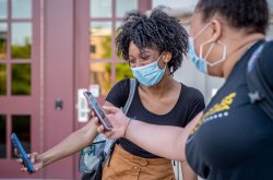 two students wearing masks checking info on their cell phones