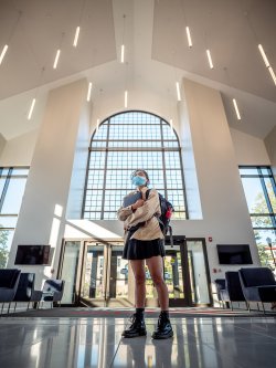 up-angle view of student standing in front of tall glass windows