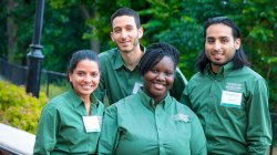 Four students in matching green shirts in a park